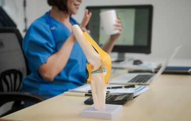 A middle-aged Asian female doctor at her desk,explaining various bone and joint diseases like...