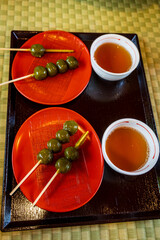 Traditional Japanese green tea and skewered matcha dango served on red plates over a tatami mat