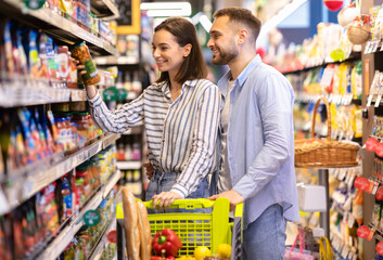 Happy Young Family Couple Shopping Groceries In The Supermarket, Cheerful Customers Choosing And...