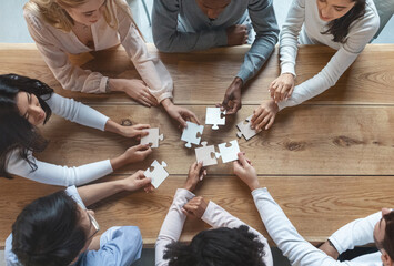 Collaboration concept, top view of young creative multiracial team sitting around table and putting...