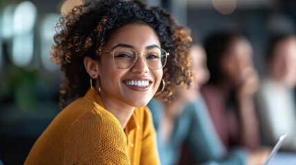 A young woman with curly hair wearing a yellow sweater, smiling and looking at the camera.