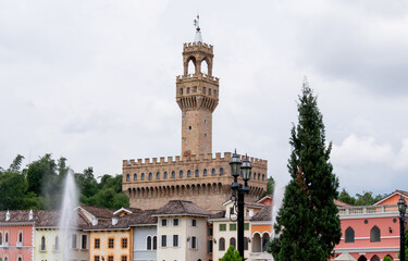 Obraz premium Photograph of a medieval castle in European style surrounded by colorful houses, fountains, and trees.