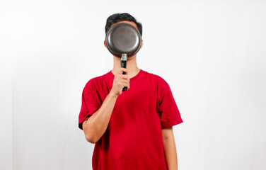 Asian man embarrassed covering face with frying pan