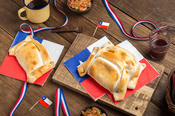Traditional Chilean Empanadas on Wooden Table With Flag Decoration and Salsa, national holidays of september 18th