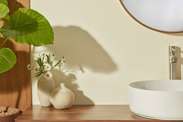 Minimal sink corner with white ceramic basin, tiny vase and green leaf shadow on wall. Wooden...