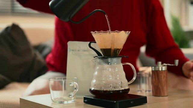 Senior man making fresh pour over coffee at home using a gooseneck kettle and glass dripper