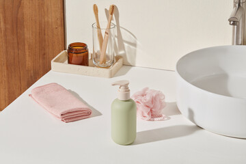 White sink counter with bamboo toothbrushes, green bottle and blush towel. Empty right-side surface...
