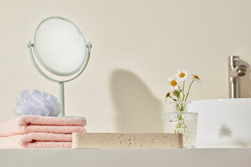 Neutral bathroom scene with daisy vase, pink towels, and white sink. Open negative space on the...