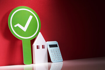 check mark tick round banner plate with small model house and calculator.