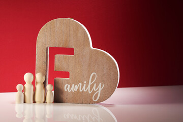 wood figurine and heart shape with word family against red background