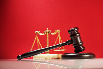 close up of the gavel hammer and libra scale against red background.