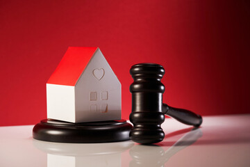 judge's gavel and small model house on mallet against red background