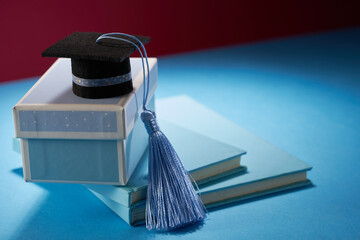 small mortarboard with blue tassel on gift box against blue background