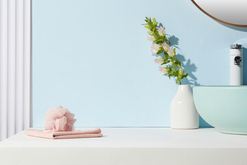 Minimalist blue bathroom with blush pink towel and bath sponge. Open counter space with soft...