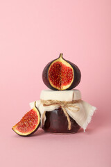 Figs and jar of jam on light pink background