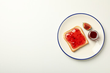 Figs, jam and piece of bread on plate on white background, space for text