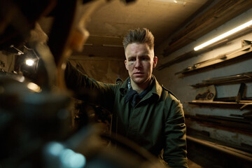 Portrait of young adult Caucasian man assembling and repairing custom bike in workshop, focused...