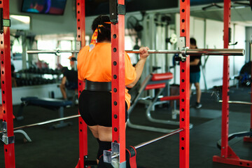 View of an overweight young Latina woman lifting weights and exercising with weights in a gym. Pushing herself. Improvement and well-being.