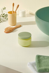 Bright white countertop with bamboo toothbrush, wooden brush, and a green cosmetic jar. Clean, natural layout highlights daily skincare tools and is perfect for organic beauty mockups.