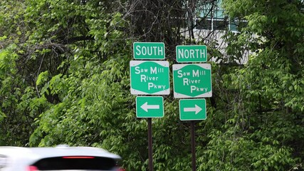 cars pass under saw mill parkway highway south and north road signs (signage sign signal arrow) westchester county new york state - Powered by Adobe