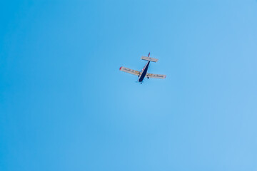 Small ultralight airplane with overhead wing and single propeller flying in sunset sky.