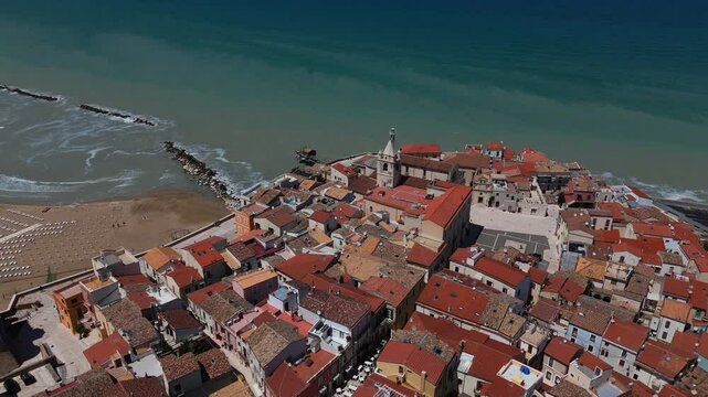 Aerial of Termoli old town with narrow alleys, historic rooftops, cathedral and seaside beach view.