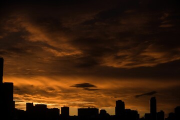 Silhouette city against cloudy sky during sunset