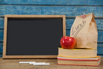 Blank blackboard with packed lunch and books