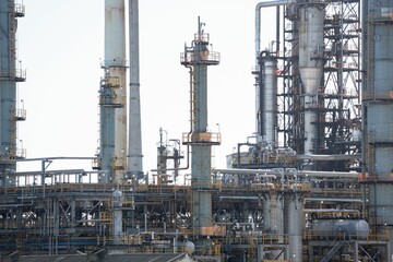 Refinery network showing flat design distillation columns, pipes, catwalks, valves under pale sky