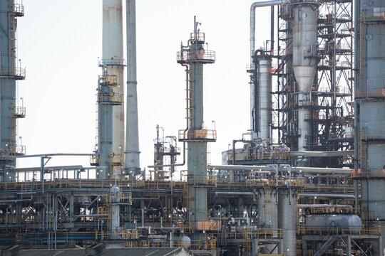 Fototapeta Refinery network showing flat design distillation columns, pipes, catwalks, valves under pale sky