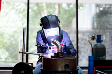 skilled indian worker working on welding machine on metal pipe in a workshop 