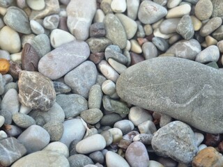 Natural smooth pebbles in various colors and sizes captured closely on the beach