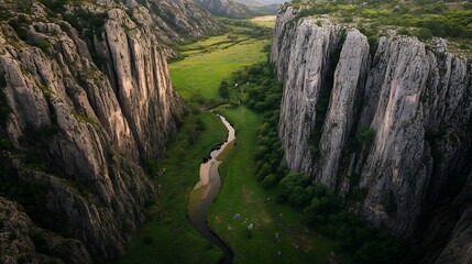 Green valley with a narrow river snaking between towering cliffs