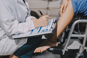 Physiotherapist checking knee of female patient stock