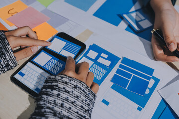 Group of young application developers analyzing uxui mobile app templates during a working meeting