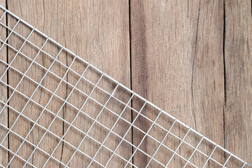 Minimalistic Composition of White Wire Grid and Rustic Wooden Surface Creating Textured Contrast...