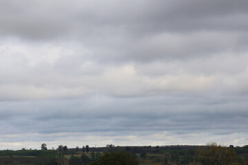 Overcast Sky with Layered Clouds Above Lush Green Landscape, Capturing the Mellow Ambiance of a...