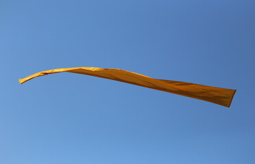 A Bright Orange Banner Floating Gracefully Against a Clear Blue Sky, Symbolizing Freedom and Celebration in Outdoor Events and Festivals