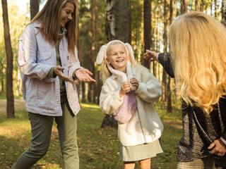 A six-year-old girl is walking in the autumn park with her mother and grandmother.
