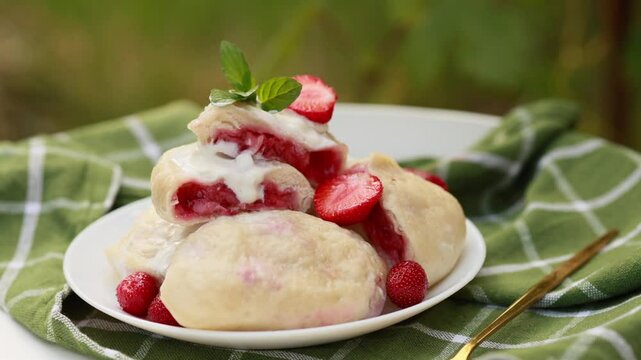Ukrainian-style varenyky bursting with strawberries. The sliced ones show vibrant red filling
