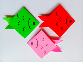 Green, pink and red fish origami isolated on white background.