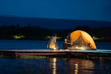 Two people sitting on a dock by a lake