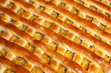 A detailed view of a golden, latticed pie, filled with savory cabbage and vegetables.