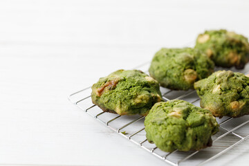 Closeup of fresh baked matcha cookies on white wooden background.