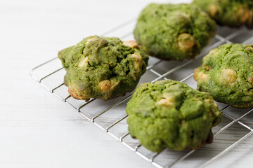 Closeup of fresh baked matcha cookies on white wooden background.