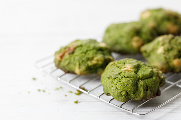 Closeup of fresh baked matcha cookies on white wooden background.