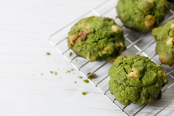 Closeup of fresh baked matcha cookies on white wooden background.