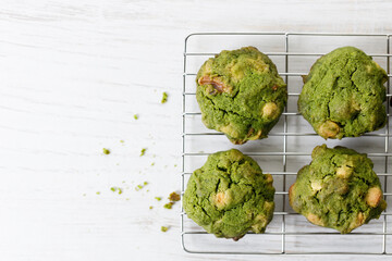 Closeup of fresh baked matcha cookies on white wooden background.