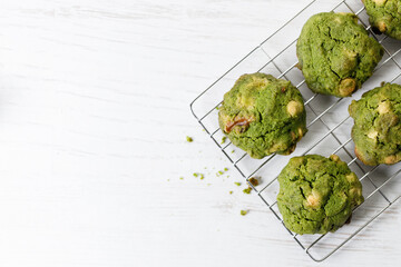 Closeup of fresh baked matcha cookies on white wooden background.