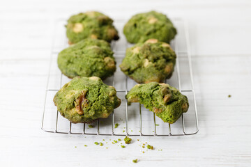 Closeup of fresh baked matcha cookies on white wooden background.